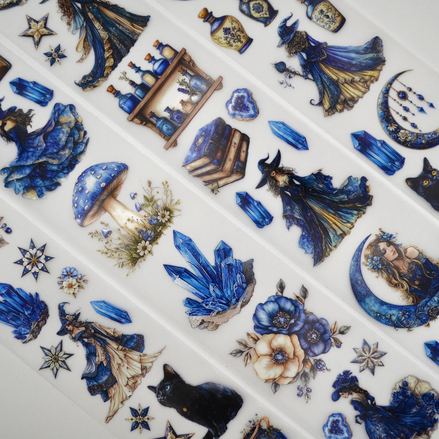 A roll of decorative PET tape stickers with a Fantasy Lunar Sorceress theme in blue and white colours, featuring illustrations of magical sorceress, black cats, spell books, crystal geodes, floral decoration and more.