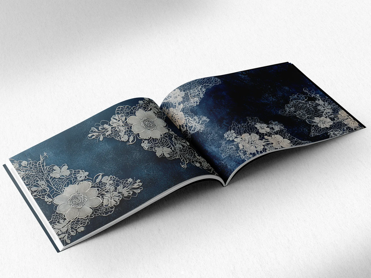 open book displaying the inner pages of a decorative paper prints pad showing dark blue doilie lace patterns