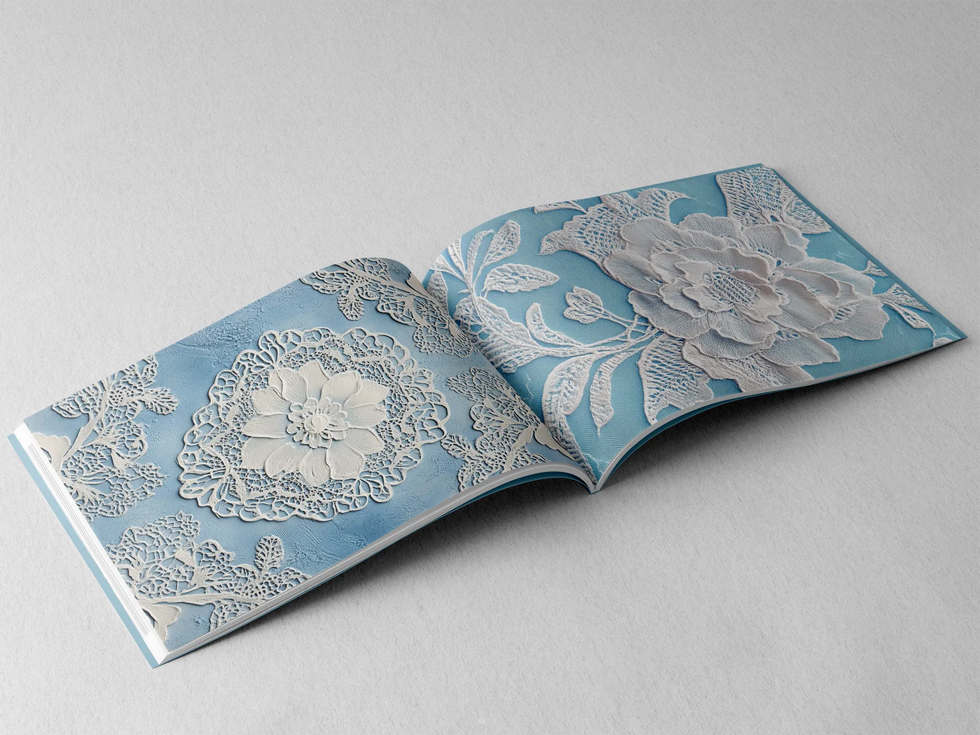 open book displaying the inner pages of a decorative paper prints pad showing blue doilie lace patterns
